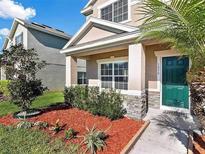 Two-story house with a green door and stone accents, landscaped yard with red mulch at 1030 Bending Oak Trl, Winter Garden, FL 34787