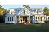 White farmhouse with metal roof, front porch, and landscaping at 2293 Eldorado Ct, Saint Cloud, FL 34771