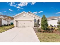 Tan house with a two-car garage and landscaped front yard at 7836 June Ln, Wildwood, FL 34785