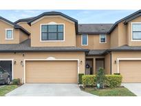 Tan two-story townhome with a two-car garage and well-manicured landscaping at 2469 Seven Oaks Dr, Saint Cloud, FL 34772