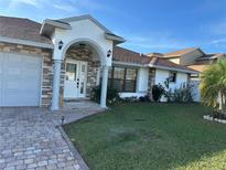 House exterior features stone accents, a paved driveway, and a well-manicured lawn at 761 Americana Ct, Kissimmee, FL 34758