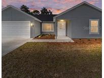 Newly constructed home with gray exterior, attached garage, and a small front yard at 13028 Ne 7Th Loop, Silver Springs, FL 34488