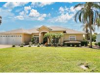 Single-story home with two-car garage, lush landscaping, and a large front yard at 1556 Auburn Oaks Ct, Auburndale, FL 33823