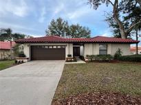 Single-story home with brown garage door, red tile roof, and landscaped lawn at 8125 N Ibiza Ct, Orlando, FL 32836