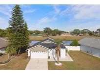 Single-story house with a two-car garage and a view of a lake at 3149 Bear Path, Kissimmee, FL 34746