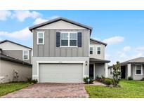 Two-story house with gray siding, brick driveway and landscaping at 4932 Mainsail St, Haines City, FL 33844