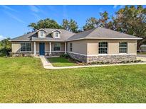 One-story home with stone accents and a landscaped lawn at 495 Guerrant St, Umatilla, FL 32784