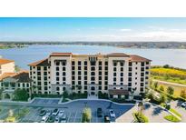 Aerial view of a luxury lakefront condo building with parking and beautiful landscaping at 16300 County Road 455 # 610, Montverde, FL 34756