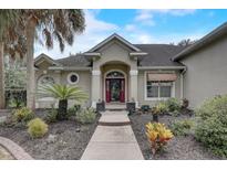 Tan house with red door, landscaping and walkway leading to the entrance at 4320 Se 106Th St, Belleview, FL 34420