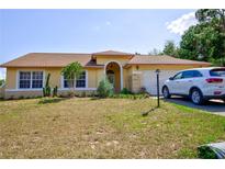 Single-story house with a yellow exterior, a car in the driveway, and a well-maintained lawn at 567 Silver Course Run, Ocala, FL 34472