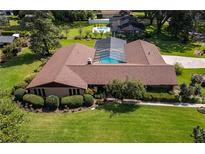 Ranch style home with brown roof, pool, and lush landscaping at 735 Se 22Nd Ave, Ocala, FL 34471