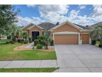 Tan two-story house with three car garage and landscaping at 9818 Sw 63Rd Loop, Ocala, FL 34481