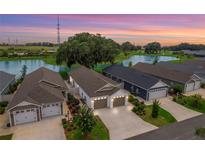 Aerial view of a community featuring houses with garages and a pond at 468 Sherell St, The Villages, FL 32163