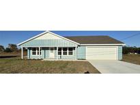 Newly constructed light blue house with a white garage door and grassy front yard at 73 Juniper Trail Loop, Ocala, FL 34480