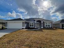 Two-story house with gray exterior, attached garage, and manicured lawn at 5838 Sw 82Nd Ln, Ocala, FL 34476