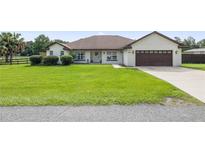 Single-story home with a brown garage door and green lawn at 13783 Se 8Th Ct, Ocala, FL 34480
