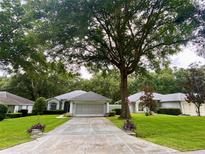 Single-story home with a two-car garage and mature tree at 9288 Sw 192Nd Court Rd, Dunnellon, FL 34432