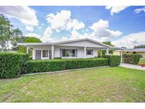 Single story home with carport, well manicured hedges, and a lush lawn at 10162 Sw 87Th Ter, Ocala, FL 34481