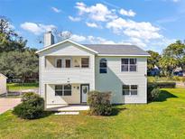 Two-story house with light yellow siding, gray roof, and a well-manicured lawn at 10 Se Chinica Drive, Summerfield, FL 34491