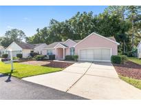 Pink one-story house with a two-car garage and landscaped yard at 11696 Sw 71St Cir, Ocala, FL 34476