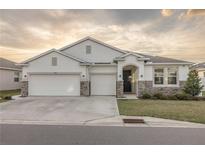 Two-story house with a three-car garage, stone accents, and a beautifully landscaped yard at 8314 Sw 59Th Ter, Ocala, FL 34476