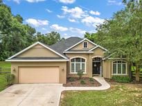 House exterior with a tan exterior, a two-car garage, and landscaping at 9680 Ne 25Th Ct, Anthony, FL 32617