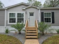 Front entrance of manufactured home with wooden stairs and landscaping at 3174 Sw 189Th Ave, Dunnellon, FL 34432