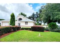 Beige house with gray roof, nicely landscaped yard at 17808 Se 115Th Ct, Summerfield, FL 34491