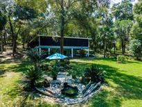 Expansive backyard with lush landscaping, a pond feature, and a screened-in porch at 24750 Ne 177Th Ter, Fort Mc Coy, FL 32134