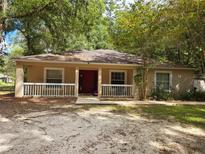One-story house with red door, white railings, and mature trees at 6995 Se 22Nd Ave, Ocala, FL 34480