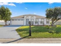 Single-story home with attached garage and landscaped lawn at 8028 Se 62Nd Ln, Ocala, FL 34472
