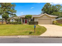 Single-story home with red door, two-car garage, and well-manicured lawn at 2215 Se 24Th Ave, Ocala, FL 34471