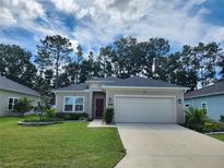 Tan house with two car garage and well-manicured lawn at 7867 Sw 74Th Loop, Ocala, FL 34481