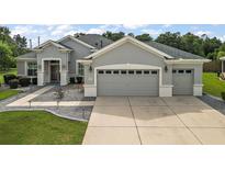 Two-story house with gray exterior, two-car garage and landscaped yard at 13944 Se 96Th Cir, Summerfield, FL 34491
