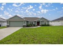 Single story home with green exterior, two-car garage, and landscaped lawn at 4978 Sw 91St St, Ocala, FL 34476
