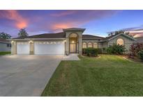 Single-story home with three-car garage, landscaped yard, and a welcoming front porch at 5159 Nw 18Th St, Ocala, FL 34482