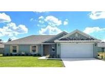 House exterior featuring a two-car garage and lawn at 3490 Sw 155 Ln, Ocala, FL 34473
