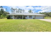 Single-story home with a spacious lawn and attached garage at 10211 Ne Highway 314, Silver Springs, FL 34488