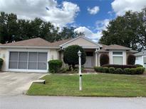 Tan one-story house with a two-car garage and well-manicured landscaping at 11613 Sw 69Th Cir, Ocala, FL 34476