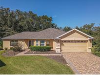 Single-story house with a tan exterior, brick driveway and landscaped yard at 13166 Se 86Th Cir, Summerfield, FL 34491