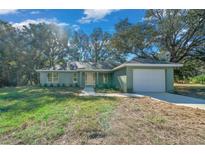 Newly constructed home with a green exterior, attached garage, and a well-manicured lawn at 19662 Sw Marine Blvd, Dunnellon, FL 34431