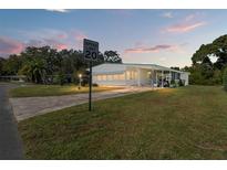 Mobile home with carport and a well-kept lawn at 903 Aloha Way, Lady Lake, FL 32159