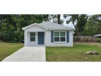 Cute one-story home with gray siding, a blue door, and landscaped lawn at 206 Nw 21St Ave, Ocala, FL 34475