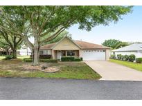 Brick ranch home with a two-car garage and mature landscaping at 9859 Sw 97Th St, Ocala, FL 34481