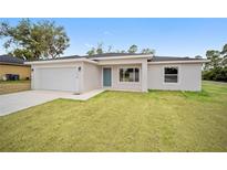 Newly constructed home with a white exterior, grassy lawn, and attached garage at 175 Fisher Way Trl, Ocklawaha, FL 32179