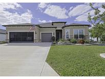 Tan two-story house with a three-car garage, landscaped lawn, and stone accents at 5564 Sw 90Th Ave, Ocala, FL 34481