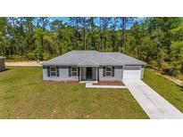 Newly constructed one-story home with gray siding, a white garage door, and a landscaped yard at 2060 Sw Yazoo Ct, Dunnellon, FL 34431