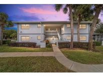 Two-story building exterior with walkway, landscaping, and palm trees at dusk at 576 Fairways Ln # M203, Ocala, FL 34472