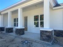 Newly constructed home with a front porch featuring stone columns and a light-colored exterior at 5912 Ne 57Th N Loop, Silver Springs, FL 34488