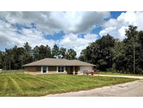 House exterior with a grassy yard and trees at 21 Maple Crse, Ocklawaha, FL 32179